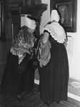 ZZE-1401 Zierikzee. Stadhuismuseum. Twee dames, gekleed in de zondagse Walcherse dracht, lezen de tekst onder het ...