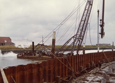 ZZG-1975 Zierikzee. Westhavendijk. Reconstructie van de loswal bij 't Luitje. Heien van meerpalen. Rechts de fabriek ...