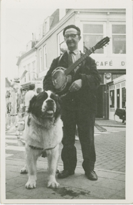 1404 De Middelburgse straatmuzikant David Smolders met banjo en zijn Sint Bernardshond Bertha voor café De Vriendschap ...