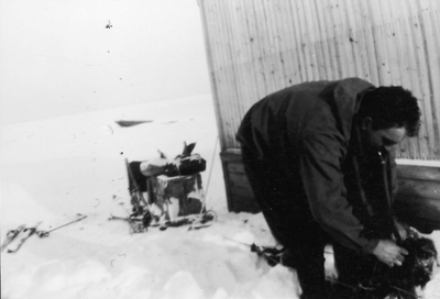 21.1-19 Een man buigt zich over een uitrusting in de sneeuw
