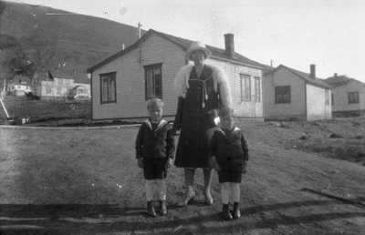 21.1-43 Een vrouw met twee jongetjes in matrozenpakjes met huizen op de achtergrond