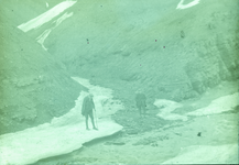 23-13-98 Twee jonge mannen in een bergachtig landschap met water en ijs op Spitsbergen