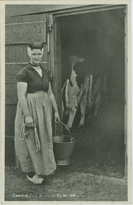 KLD-P-179 Zeeland, bij den stal. Een vrouw in Zeeuwse dracht bij een koeienstal
