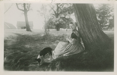 KLD-P-191 Een vrouw in Walcherse dracht zit met een hond onder een boom