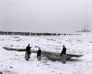 555 NFR Drie vrouwen in dracht staan op het strand bij Westkapelle dat door sneeuw is bedekt.