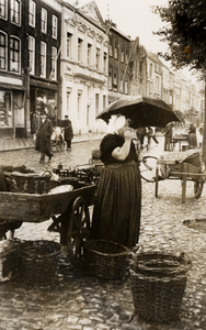 1167 De zeer bekende visvrouw Mevr. G. de Nooijer-van Eenennaam, in de regen bij haar karretje op de Nieuwendijk