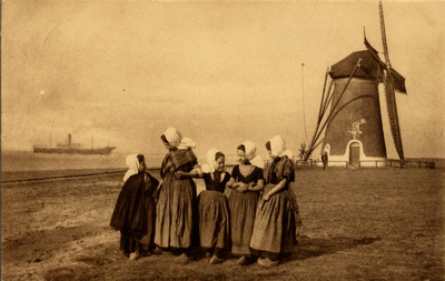 12861 'Zeedijk 'Westkapelle'. Vijf meisjes in klederdracht met de molen en een schip op de achtergrond