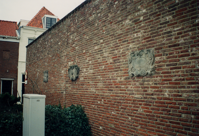 13345 Drie gevelstenen op een muur in de Schutterijstraat. Links op de achtergrond ziet men de Scherminkelstraat.