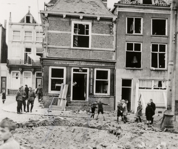 17084 Tweede Wereldoorlog. Bomkrater op het Bellamypark. De zijgevel van het Beursgebouw en rechts een pand aan de ...