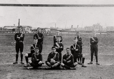 17287 Elftal van voetbalclub 'De Eilandboys'. Rechts op de achtergrond ziet men het station en links daarvan een ...