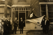 26157 D.L.H. van Raalte met de vlag van 'Vlissingen Vooruit', opgericht in 1902, en dhr. van Niftrik drukken elkaar de ...