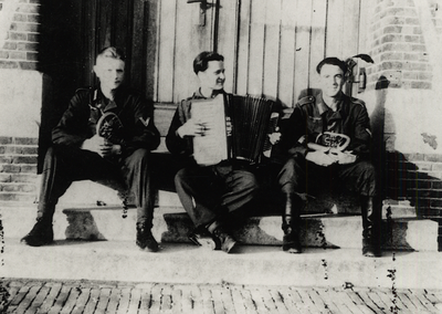 33113 Tweede Wereldoorlog. Boulevard Bankert. Drie Duitse soldaten op de stoep voor de Zeevaartschool. De accordeonist ...