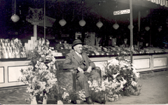 34822 Op de Vlissingse kermis. Roelof Vinke, ook wel Nougat Vinke genoemd, tussen de bloemen, waarschijnlijk bij zijn ...