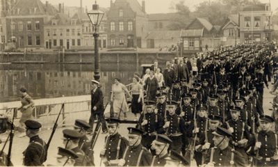 35446 Parade van de zeemacht. Vanaf de Schipbrug marcheert men de Houtkade in. Op de achtergrond ziet men de Dokkade