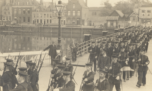 35447 Parade van de zeemacht. Vanaf de Schipbrug marcheert men de Houtkade in. Op de achtergrond ziet men de Dokkade