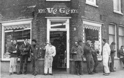 37908 Kruidenierswinkel van de Végé in de Glacisstraat, hoek Van Dishoeckstraat. Werknemers van de Kon. Mij. de Schelde ...