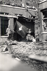 41073 Tweede Wereldoorlog. Duitse soldaten van de brandweer poseren met vlag met het wapen van Vlissingen bij een door ...