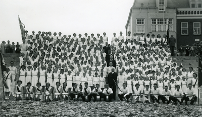 47398 Groepsfoto van de gymnastiekvereniging VTV en de drumband op het badstrand voor Boulevard Evertsen, t.g.v. het ...