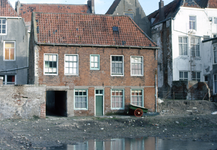 51528 Braakliggend terrein na de sloop van de oude huisjes van Hofje de Pauw.Het pand (midden), met toegangspoort van ...