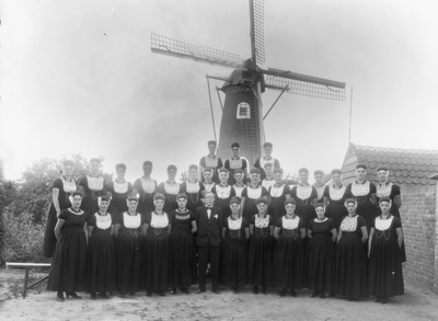 9341 Groepsfoto van het Westkappels dameskoor onder leiding van dirigent Piet de Rooij. Op de achtergrond de korenmolen ...