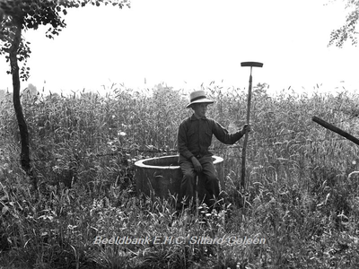ehc_gp_092 Jongen met schoffel in de hand rust even uit op een waterput voor het vee in het Gehucht Amerika, Gemeente Horst