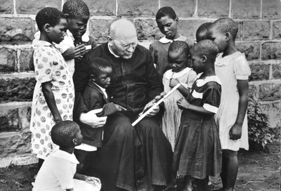 230382 Priester met geïnteresseerde kinderen in de omgeving van Kinshasa (Congo)