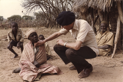 140081 Pater Henk Buijs onderzoekt een bejaarde vrouw in een dorpje nabij Kapepe, Zambia