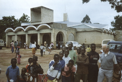 140087 Broeder Jan Campschreur met Afrikaanse kinderen voor de door hem gebouwde Bischopskerk te Kasama, Zambia