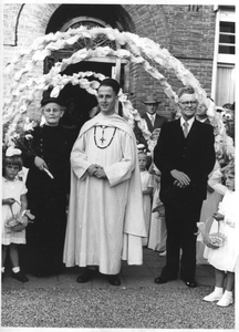 140234 Pater Henk Kager met ouders onder de ereboog na zijn eerste plechtige H. Mis voor de Sint Laurentiuskerk te ...
