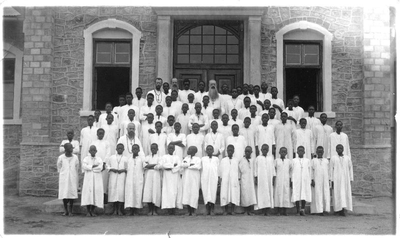 140372 Groepsfoto van pater Jan Meeuwsen met collega's en de internaatsleerlingen te Nyegezi in Tanzania