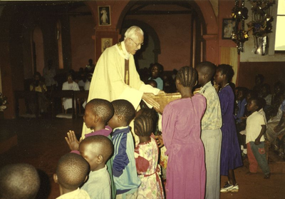 140434 Pater Hans Peters deelt de gaven voor de offerande uit op Afrikaanse wijze in de parochiekerk te Mabamba in Uganda