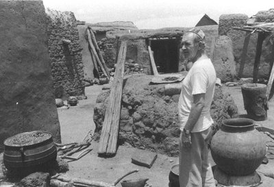140499 Pater Gerard Smulders in een dorp met lemen gebouwen in de missie te Ghana