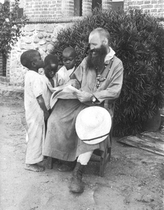 140659 Pater Bernard Zuure met enkele jongetjes bij de kerkmuur te Mpala in Kenia