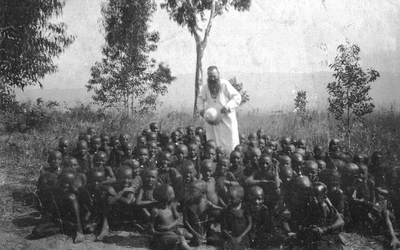 140662 Groepsfoto van pater Bernard Zuure met een grote groep zittende jongens in zijn missiegebied in Burundi