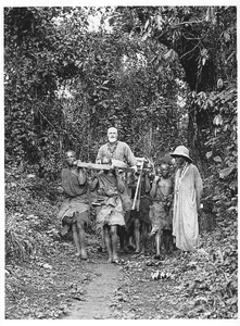 140673 Pater Martien van der Wee gezeten in een draagstoel op tocht door de jungle van Rwanda
