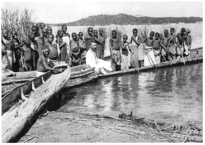 140674 Pater Moyoni, Gerard van Muyen, met lokale bewonders in kano's aan de rand van het Tanganyika-meer te Kirando in ...