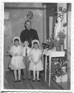 236014 Pater Henk Huijbers o.m.i. (1916-2002) met de eerste drie communicantjes te 'Our Lady of Lourdes' (Canada)