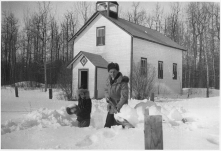 236021 Sneeuwvrij maken van het pad naar het kerkje, op Paasochtend, door pater Knapen o.m.i. (1919-1990) en misdienaar ...