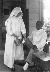 186447 Zuster verbindt een lepra-patiënt in de Majella Stichting te Paramaribo (Suriname)