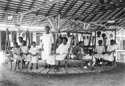186506 Melaatse meisjes op vakantie genieten in de draaimolen, Sint Gerardus Majellastichting Paramaribo (Suriname)
