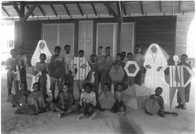 186507 Jongeren met zelfgemaakte vliegers in de melaatsenkolonie Sint Gerardus Majellastichting te Paramaribo (Suriname)