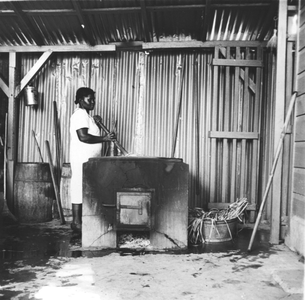 186595 Koken van het stro in de vlechtschool te Paramaribo (Suriname)