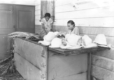 186602 Het roken van de gemaakte hoeden in de vlechtschool te Paramaribo (Suriname)