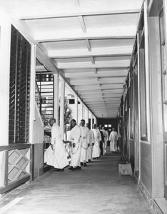 186650 Paters lopen het Te Deum zingend van refter naar oratorium via de houten trap (Suriname)