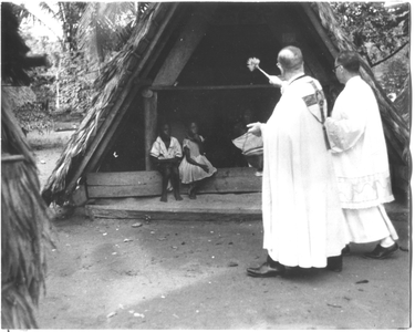 186657 Monseigneur Kuijpers en pater Coppelmans zegenen een bosnegerhut (Suriname)