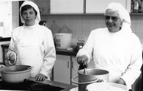102093 Zuster Maria Leunissen en zr. Gabriëlle Emke tijdens het koken in de Stad Gods te Amsterdam