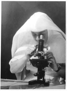 242080 Zuster kijkt door de microscoop in een kliniek, Congo