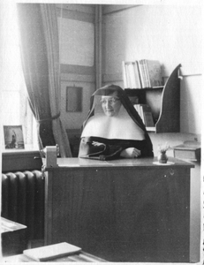 242117 Zuster Jeanne achter het bureau van de school aan de Dobbelmannweg te Nijmegen