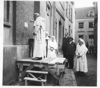 196012 Pater Koolen bevestigt de gedenksteen van het doorgangshuis van huize Bethlehem te Nijmegen in aanwezigheid van ...