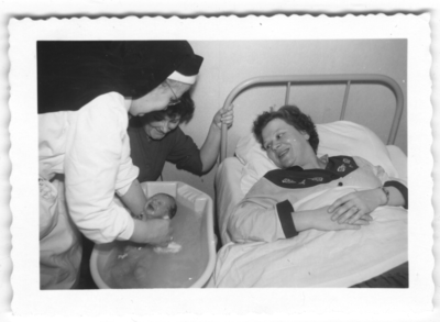196123 Moeder kijkt toe hoe de zuster van de kraamzorg Nijmegen haar baby wast